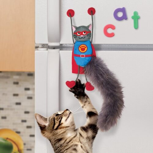 Gato jugando con el KONG Connects Magnicat pegado magnéticamente a un refrigerador blanco